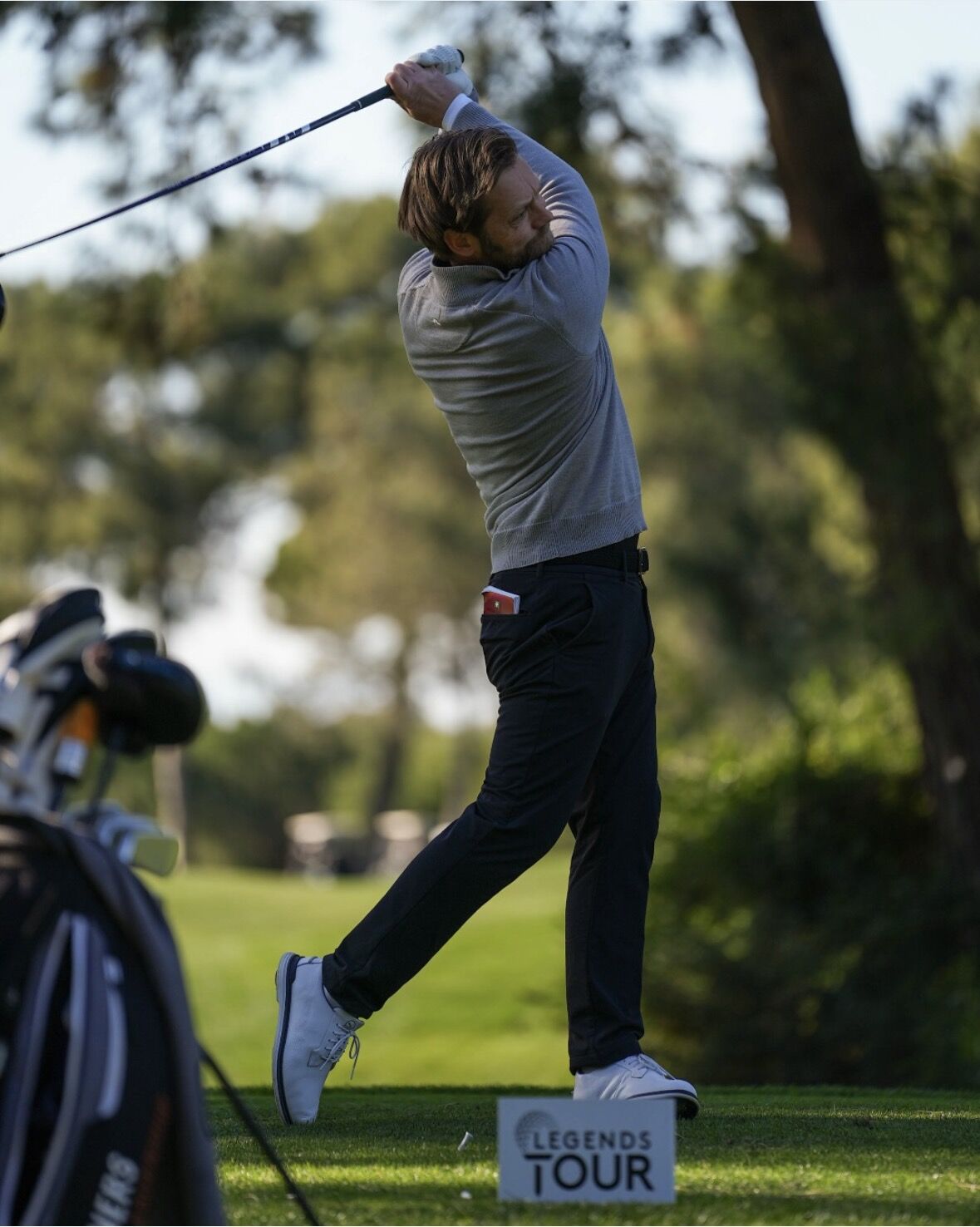 Fredrik avslutar ett golfslag på banan, med en Legends Tour-skylt i förgrunden.